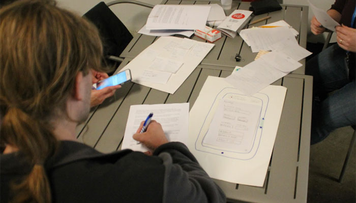 Image of a group of researchers testing paper protypes of a mobile design.